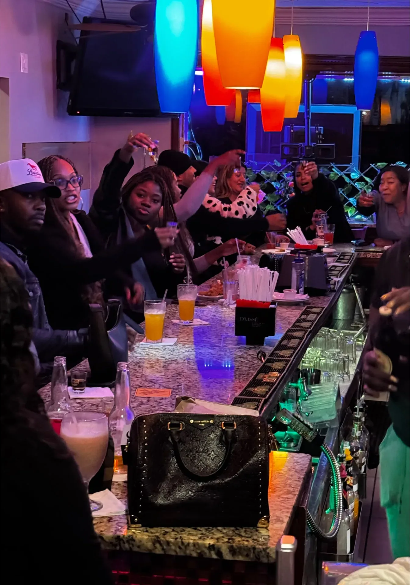 Guests raising a toast beneath colorful lights at the Spices Negril bar